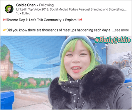 Toto je snímek obrazovky videa z LinkedIn, na kterém Goldie Chan dokumentuje své cesty. Text nad videem říká „Toronto Day 1: Let’s Talk Community + Explore! Věděli jste, že každý den se konají tisíce setkání?.. vidět víc". Video ukazuje Goldie před nástěnnou malbou na cihlové zdi. Nástěnná malba ukazuje jasně modrou oblohu a hnědé útesy pokryté jasnou zelení. Goldie se objeví od hrudi nahoru. Je to asijská žena se zelenými vlasy. Má na sobě modrou pletenou čepici a černou bundu s chlupatým límcem. V pravém horním rohu videa se #DailyGoldie zobrazí v broskvovém textu se zeleným obrysem.